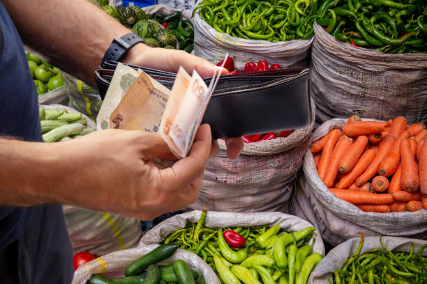istock Man taking money from his wallet in front of vegetable counter 1286696116