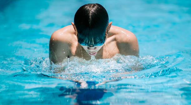 vue avant nageur chinois d’athlète natation dans la piscine - splashing color image front view head and shoulders photos et images de collection