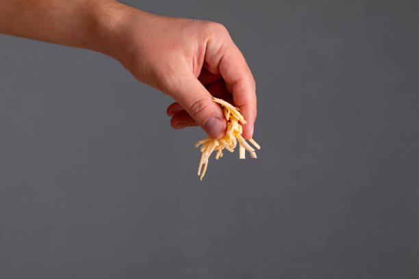closeup of man hand sprinkle grated cheese over dark background. healthy food. - recipe ingredient grater cheese grater imagens e fotografias de stock