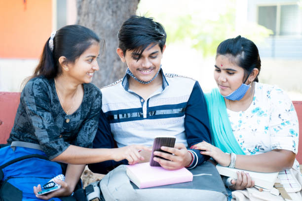 istock Three friends while sitting at college laughing by looking into mobile phone - concept of students internet, mobile addiction, online bullying or gossips at university campus. 1286702126