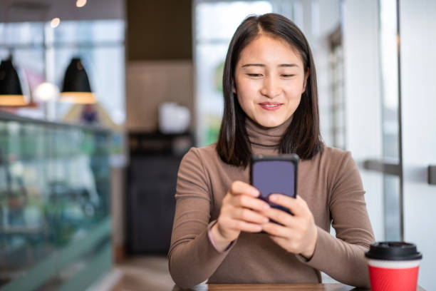 istock Young Asian woman using smart phone in coffee shop 1286703445