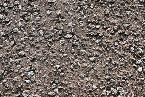 Close up image of a rough asphalt road surface, with gravel for grip.
