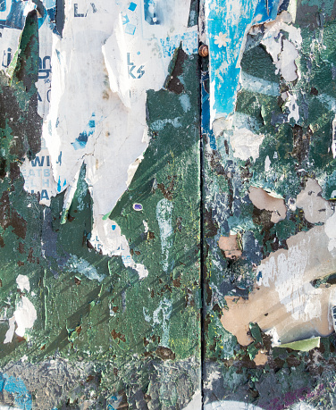 Close-up of an ageing urban surface, with fading and peeling paint, markings and ripped paper.
