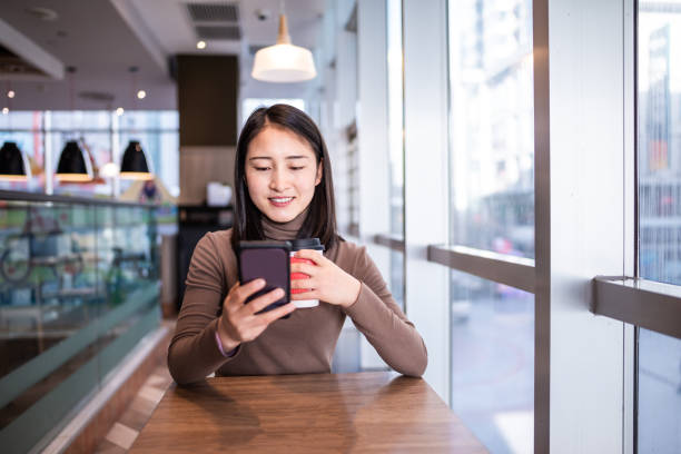 istock Young Asian woman using smart phone in coffee shop 1286704683