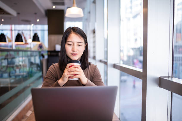 istock Young Asian woman using laptop in coffee shop 1286705708