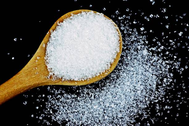 istock Sugar and wooden spoon - black background. 1286705845