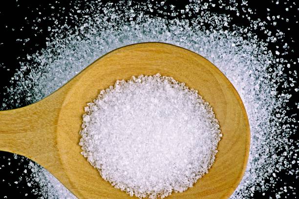 istock Sugar and wooden spoon - black background. 1286706403