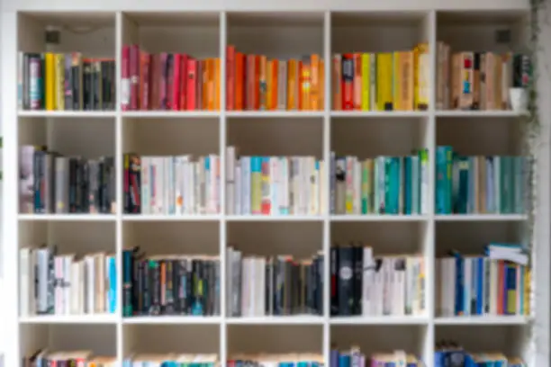 Photo of Blurred image of white wooden bookcase filled with books