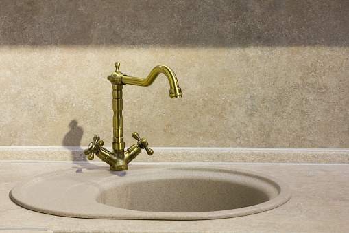 round porcelain tile kitchen sink on the kitchen countertop and retro brass faucet.