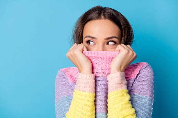 Photo of curious girl close cover pullover collar chin mouth look copyspace isolated blue color background Photo of curious girl close cover pullover collar chin mouth look copyspace isolated blue color background. turtleneck photos stock pictures, royalty-free photos & images