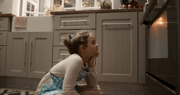 I can't wait for them to be done Cropped shot of a little girl waiting patiently in front of the oven impatient stock pictures, royalty-free photos & images