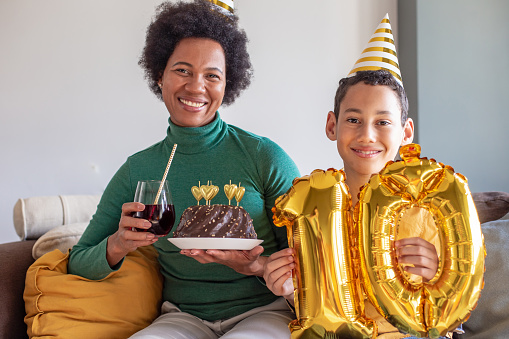 Portrait of mother and her son are at home holding birthday cake and they are looking at camera