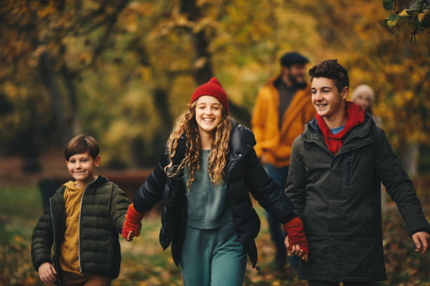 istock Happy children holding hands, walking in forest. Their parents are behind them. 1286713202