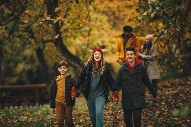 istock Sister and two brothers holding hands and walking in forest path. Their parents are behind them. 1286713233