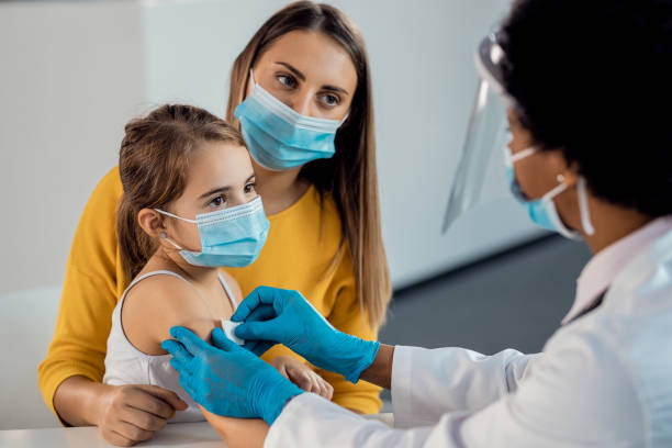Little girl getting adhesive bandage on her arm after vaccination at medical clinic. Female doctor placing adhesive bandage on little girl's arm after vaccination. Focus is on girl. bandage photos stock pictures, royalty-free photos & images