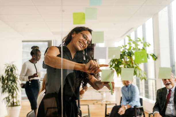 istock Young latin woman putting on a post it during brainstorming in office 1286717904