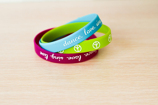 colored bracelets with inscriptions on beige background