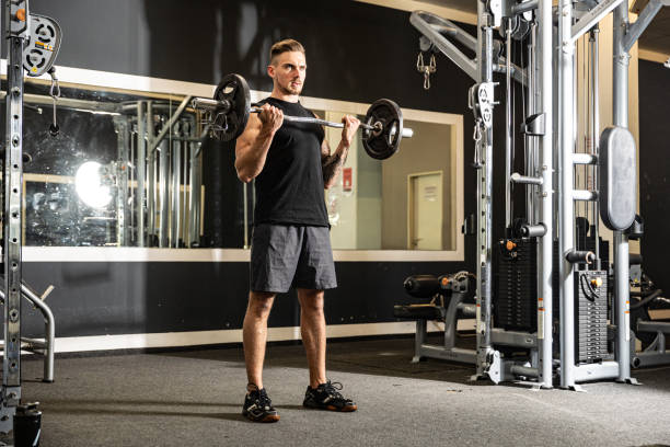 Athletic man does fitness exercises with weights in a gym