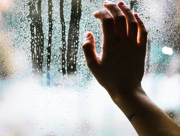 istock hand holding window glass with raindrops 1286721577