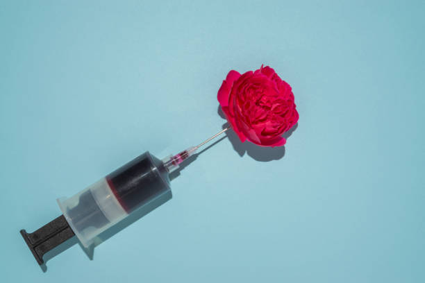 istock Big syringe creative concept with red roses. Minimal copy space on light blue background. 1286722123
