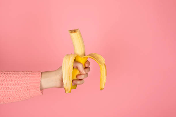 istock Female hand holds bright yellow bitten banana 1286722741