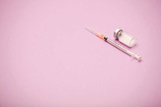 istock syringe with vaccine bottle, pink background 1286723352