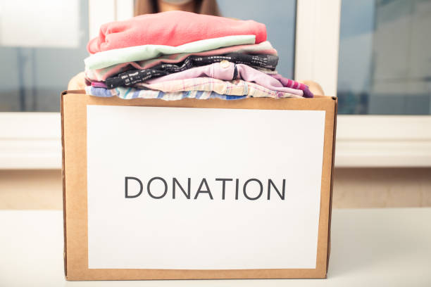 istock Volunteer girl with a donation box with second hand clothes 1286726079