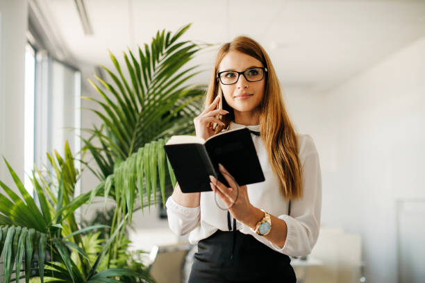 istock Young secretary holding note pad and talking on the phone 1286726084