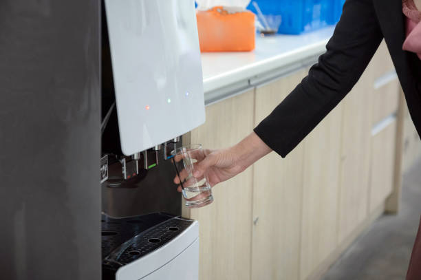 Hand holding glass filling cool water from water dispenser Woman hand holding glass filling cool water from water dispenser woman pushing tire stock pictures, royalty-free photos & images