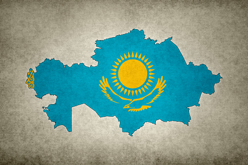 Grunge map of Kazakhstan with its flag printed within its border on an old paper.
