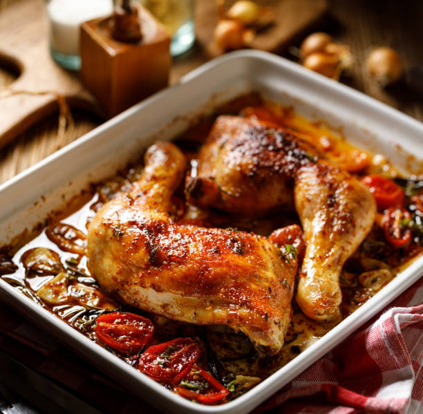 istock Oven roasted chicken leg quarters with garlic, cherry tomatoes and herbs in a baking dish 1286733207