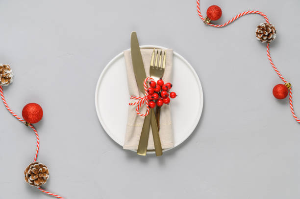 istock Festive table setting with white plate, golden cutlery and xmas decorations on light gray tabletop 1286733285