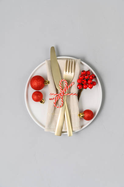 istock Festive table setting with white plate, golden cutlery and xmas decorations on light gray tabletop 1286733291