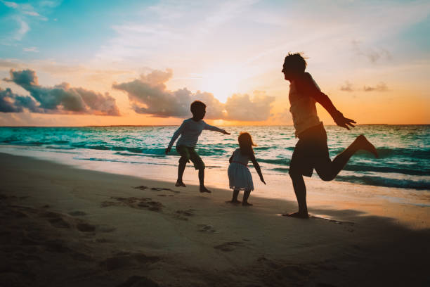 istock happy father with kids jumping from joy at sunset beach 1286733972
