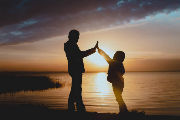 istock happy mother with daughter high five at sunset on lake 1286733995