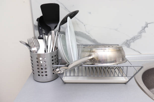 istock Dish rack with clean dry dishes and pan, different utensils on kitchen counter, washing and drying kitchenware 1286738295