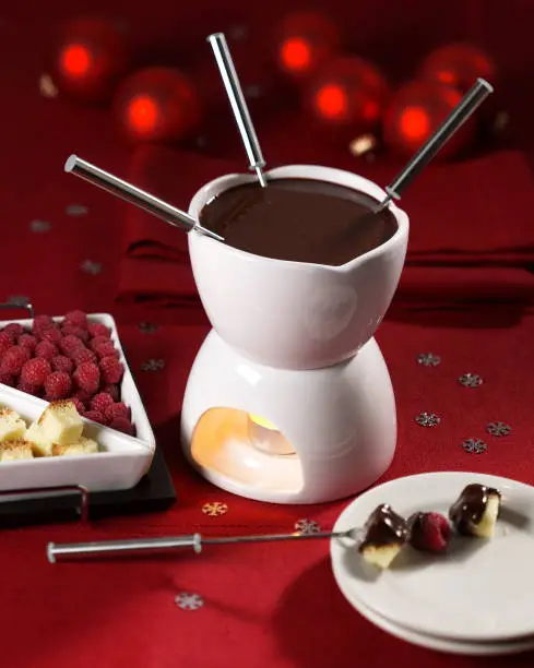 Chocolate fondue with raspberries and cake pieces and a holiday feel.