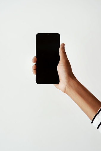 Cropped shot of a woman using a smartphone against a white studio background
