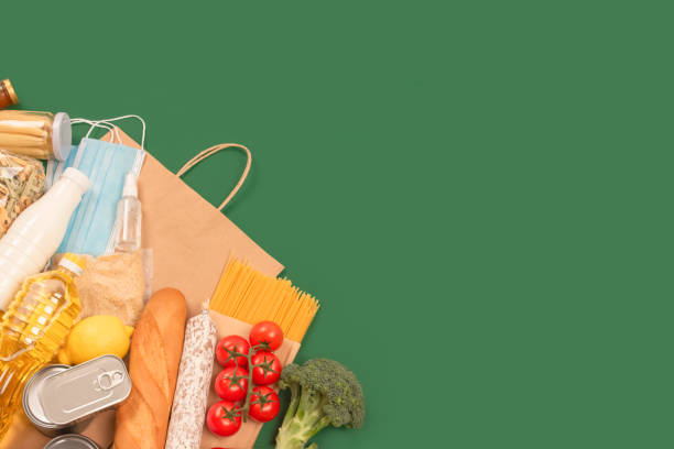 istock Flat lay composition with food and medicines donations on green background with copyspace - pasta, fresh vegatables, canned food, baguette, cooking oil. Food donations and food bank concept 1286742497