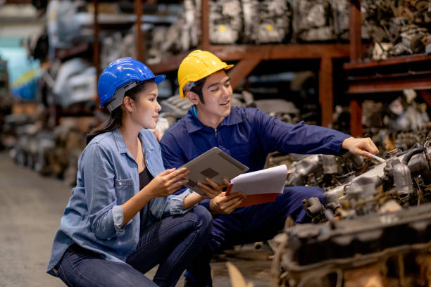 Close up Asian warehouse woman discuss together with factory worker man by sitting in automotive parts workplace area Close up Asian warehouse woman discuss together with factory worker man by sitting in automotive parts workplace area. Concept of good management and support system for industrial business. car plant stock pictures, royalty-free photos & images