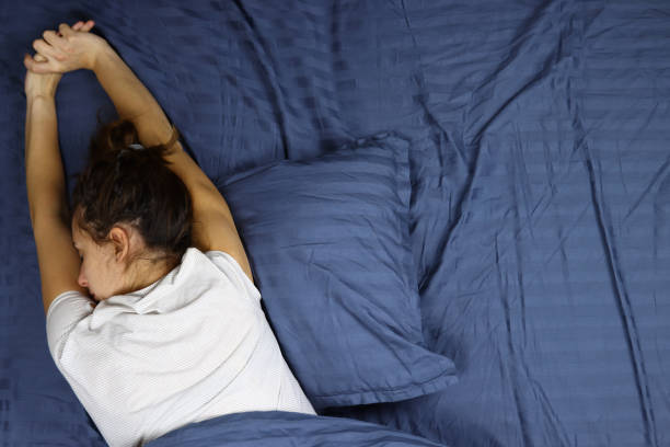 istock Young woman wakes up, stretches in bed 1286745067