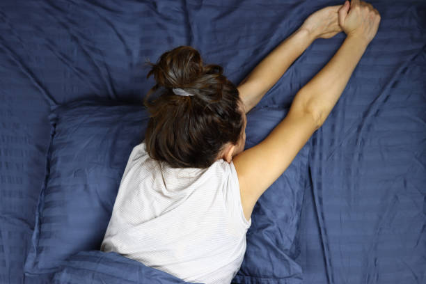 istock Young woman wakes up, stretches in bed 1286745586
