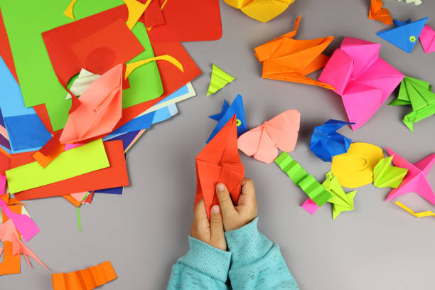istock Children's hands make origami crafts from colored paper 1286746328