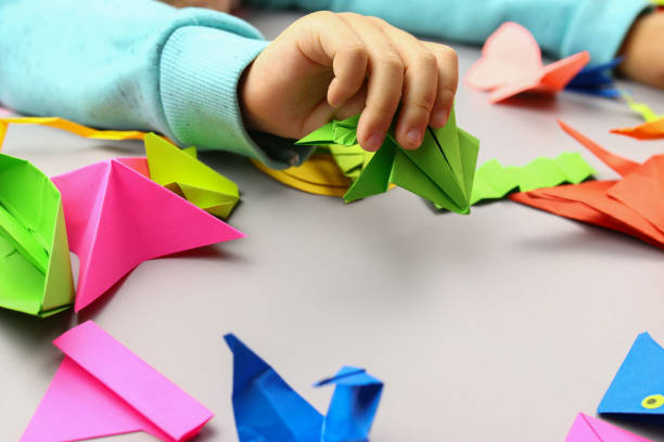 istock Child makes origami crafts from colored paper, hands close-up 1286746403