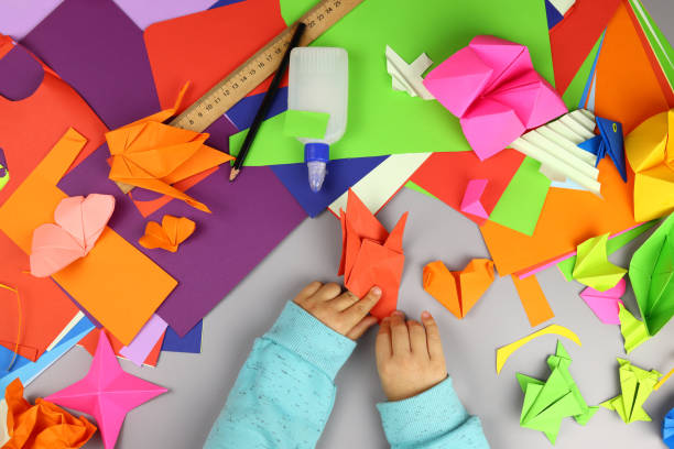 istock Child makes origami crafts from colored paper, hands close-up 1286746419