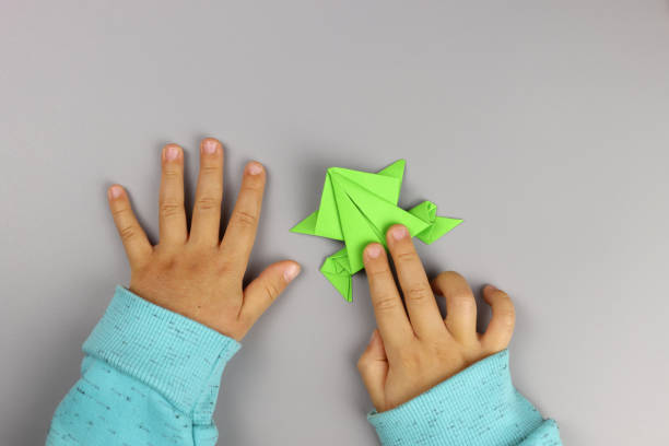 istock Child makes origami crafts from colored paper, hands close-up 1286746462
