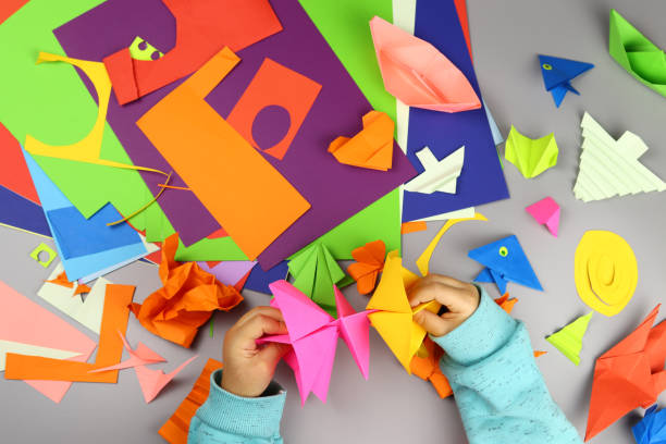 istock Children's hands make origami crafts from colored paper 1286747055