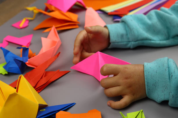 istock Children's hands make origami crafts from colored paper 1286747126