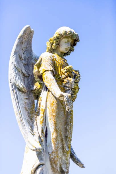 istock Angel, old statue of angle with flowers, background with copy space 1286751234