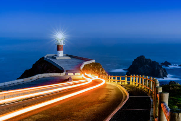nachgestellte autolichter führen nachts zum leuchtturm von cabo ortegal - atlantic coast flash stock-fotos und bilder